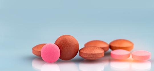 Czerwone i różowe tabletki na niebieskim tle.