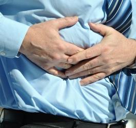 Mężczyzna chwyta się za brzuch, boli go żołądek.