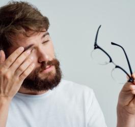 Mężczyzna pociera oko dłonią, dokucza mu drganie powieki.