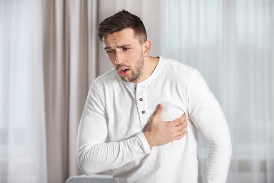 Mężczyzna chwyta się za klatkę piersiową, męczą go duszności.