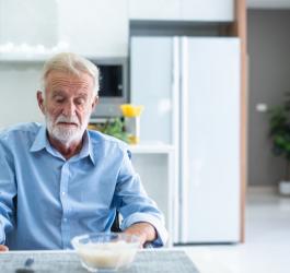 Starszy mężczyzna z dysfagią ma problem ze zjedzeniem posiłku.