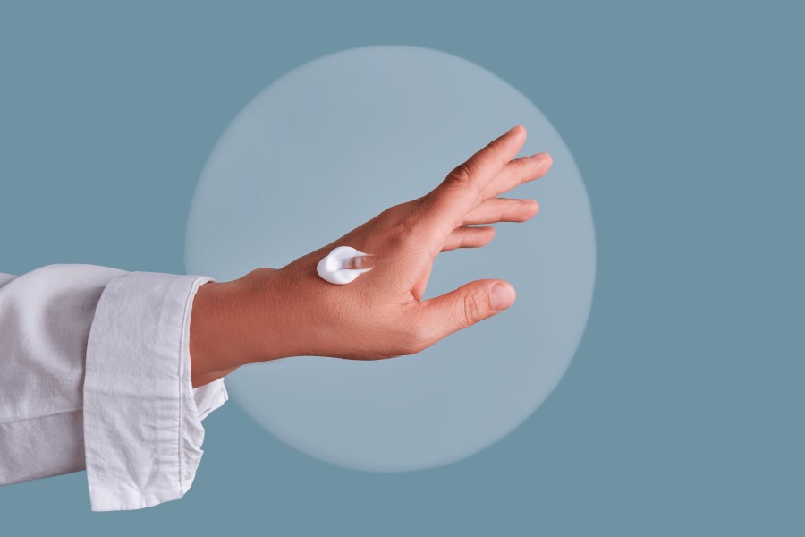 Kobieta nałożyła krem emolientowy na dłoń.