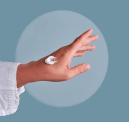 Kobieta nałożyła krem emolientowy na dłoń.