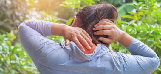 Kobieta odczuwa ból karku związany z fibromialgią.