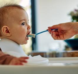 Niemowlę karmione kaszką przez rodzica.