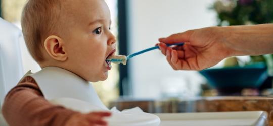 Niemowlę karmione kaszką przez rodzica.