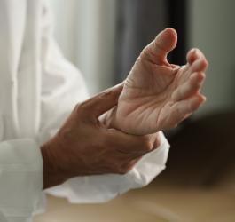 Starsza osoba trzyma się za nadgarstek, odczuwa w nim ból z powodu gośćca.