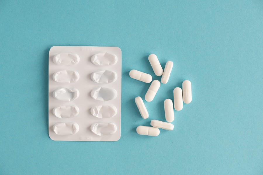 Białe kapsułki obok pustego blistra.