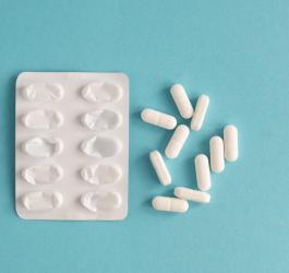 Białe kapsułki obok pustego blistra.