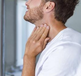 Mężczyzna trzyma się za szyję, choruje na chorobę Hashimoto.