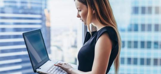 Młoda kobieta korzysta z laptopa w biurze.