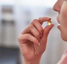 Kobieta przyjmuje kapsułkę suplementu witaminowego.