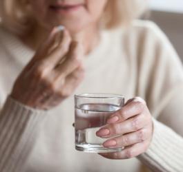 Dojrzała kobieta zażywa tabletkę będącą hormonalną terapią zastępczą.