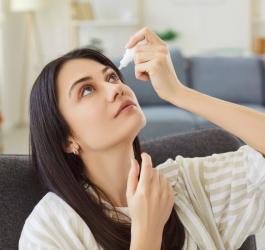 Kobieta zakrapla sobie krople do oczu.