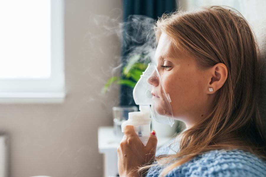 Kobieta wykonuje inhalację na zatoki za pomocą inhalatora.