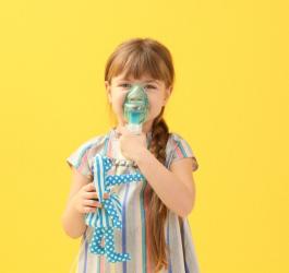 Dziewczynka korzysta z inhalatora, w drugiej ręce trzyma ulubioną zabawkę.