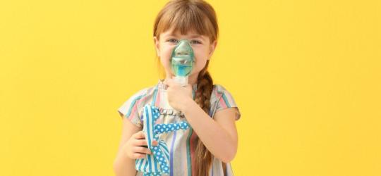 Dziewczynka korzysta z inhalatora, w drugiej ręce trzyma ulubioną zabawkę.
