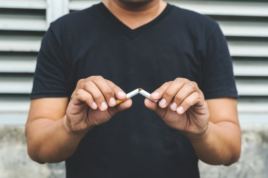 Mężczyzna przełamuje papierosa, postanawia rzucić palenie.
