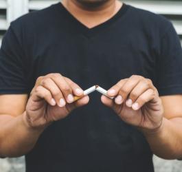 Mężczyzna przełamuje papierosa, postanawia rzucić palenie.