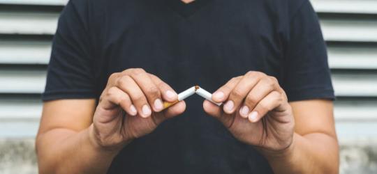 Mężczyzna przełamuje papierosa, postanawia rzucić palenie.