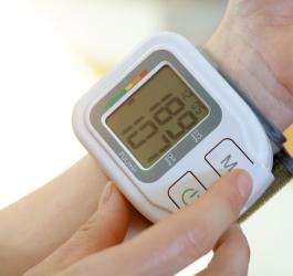 Założony na rękę ciśnieniomierz nadgarstkowy, pokazuje wysokie wartości ciśnienia tętniczego.