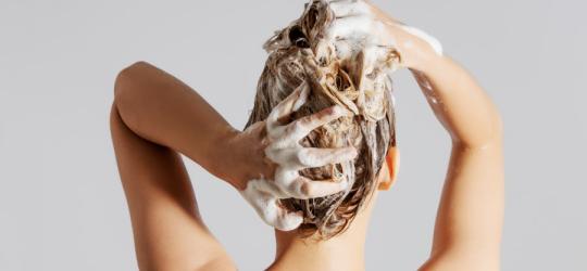 Kobieta wykonuje peeling skóry głowy.