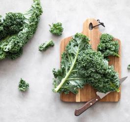 Liście świeżego jarmużu na drewnianej desce i blacie.