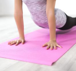 Kobieta w stroju sportowym ćwiczy jogę na różowej macie do ćwiczeń