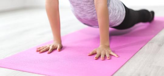 Kobieta w stroju sportowym ćwiczy jogę na różowej macie do ćwiczeń