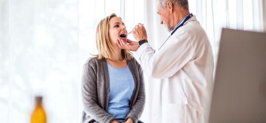 Pacjentka podczas badania przez laryngologa, który sprawdza stan gardła i migdałków.