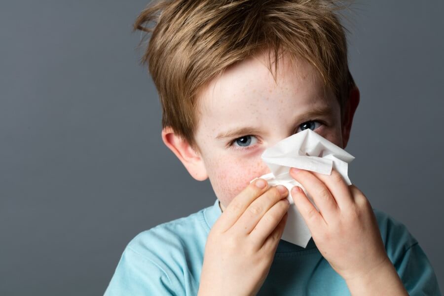 Dziecko ma katar, wydmuchuje nos w chusteczkę higieniczną.