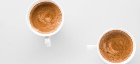 Dwa białe kubki z kawą bezkofeinową leżą na blacie kuchennym