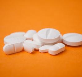 Tabletki zawierające ketoprofen na pomarańczowym tle.