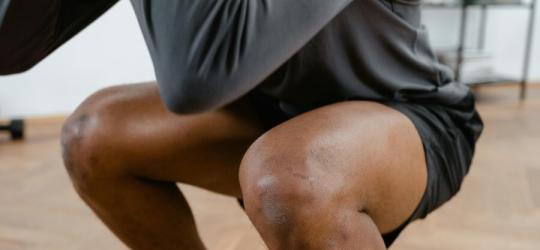 Mężczyzna wykonuje głęboki przysiad.