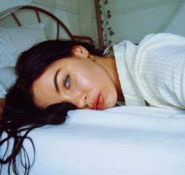 Młoda kobieta leży na łóżku, wygląda na przemęczoną.