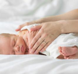 Mama przykrywa kocykiem noworodka po kąpieli.