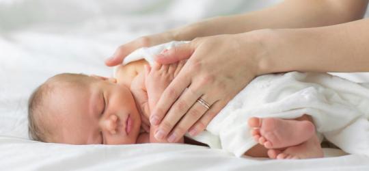 Mama przykrywa kocykiem noworodka po kąpieli.