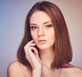 Młoda kobieta spogląda w stronę obiektywu.