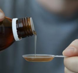 Mężczyzna nalewa na łyżeczkę krople żołądkowe.