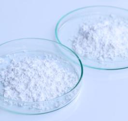 2 laboratoryjne spodki z wysypanym kwasem bornym w postaci białego proszku.