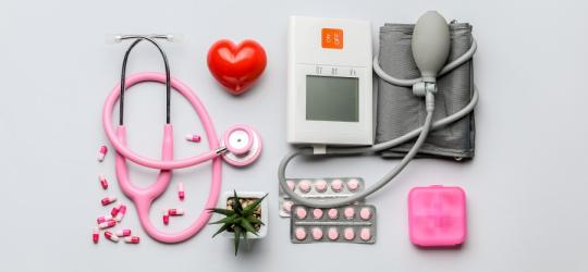Leki na nadciśnienie obok ciśnieniomierza, stetoskopu i kasetki na leki.