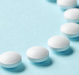 Białe tabletki ułożone na błękitnym tle.