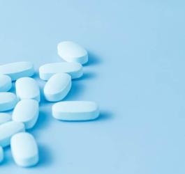 Niebieskie leki na potencję rozsypane na niebieskim tle.