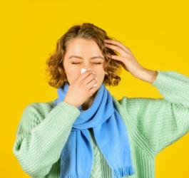 Kobieta w szaliku wydmuchuje nos, ma zapalenie zatok.