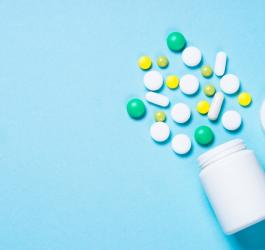 Kolorowe tabletki wysypane z białej fiolki na leki.