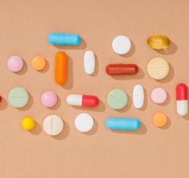 Kolorowe tabletki i kapsułki na ceglanym tle.