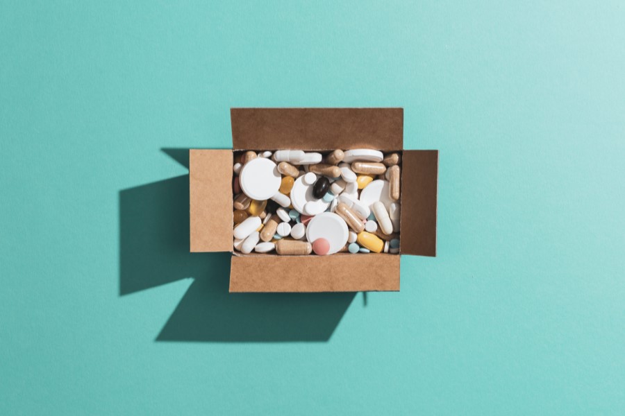 Rozmaite leki wsypane do kartonowego pudełka.
