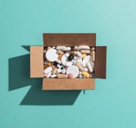Rozmaite leki wsypane do kartonowego pudełka.