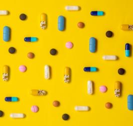 Kolorowe tabletki na żółtym tle.