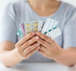 Kobieta trzyma w dłoniach kilka blistrów różnych leków.